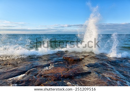 Big Wave Splash on Lake Superior in the Upper Peninsula of Michigan. Waves break against a rocky shoreline near Pictured Rocks National Lakeshore in Munising, Michigan.