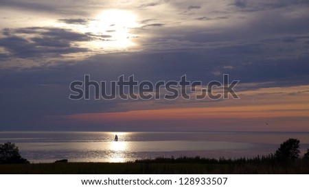 Sailboat passing the Sun's water ray as it passes towards what will later become a thundercloud.