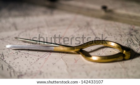 Pair of compasses used for navigation on a sea map with low depth of field