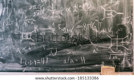 Blackboard containing Einstein field equations, Hamiltonian and Gauss\' Law.
