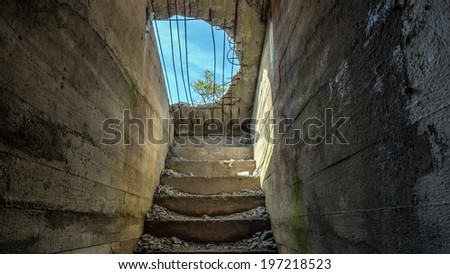 looking up at the blue sky through a hole in the concrete from a bunker or dungeon