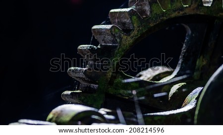 Dark rusty spider infested cogwheels from a harbor winch at night. Can be used to illustrate a nightmare, steampunk or dark industry. Black background
