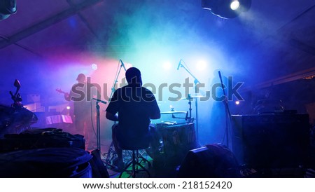 Rock band playing with smoke, seen from behind