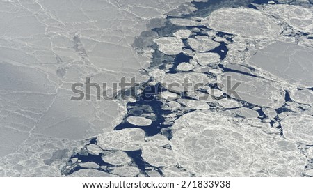 crack in ice sheet forming sea ice and icebergs in the arctic sea, seen from a plane