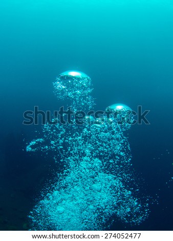 Bubbles from a SCUBA diver slowly rise to the surface, expanding and breaking up again. Photo taken during a dive in Bali, Indonesia.