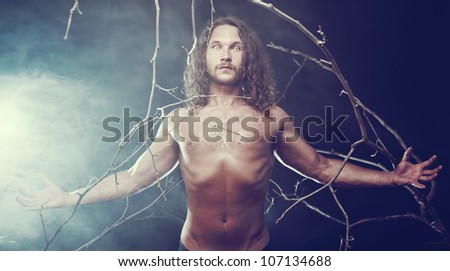 Muscular naked man with scary eyes in the forest, Halloween theme