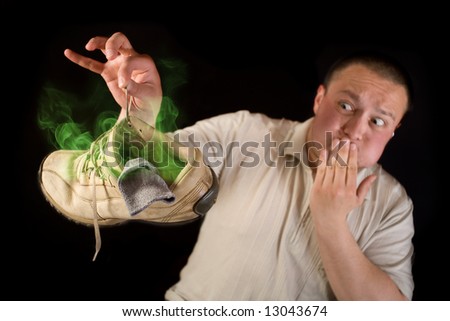 Shocked man holding smelling shoe isolated on black background