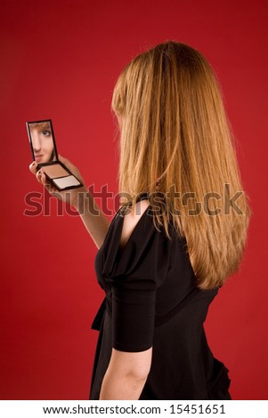 Beautiful girl looking in mirror, face in reflection