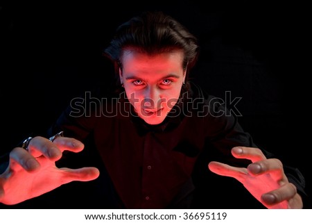 Scary vampire stretching his hands to catch a victim, isolated on black background