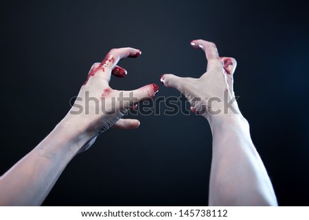 Grey skin bloody zombie hands, studio shot over gray background