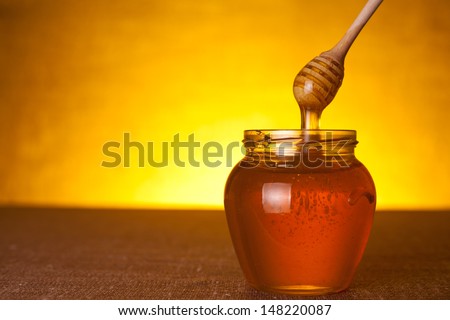 Honey jar with dipper and flowing honey
