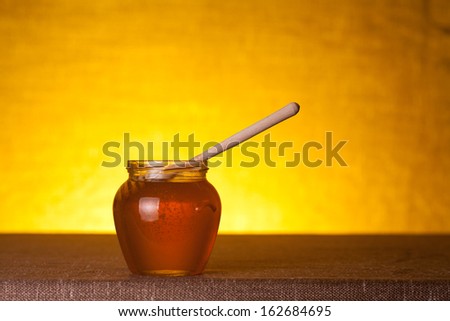 Honey jar on canvas table, studio shot over warm background