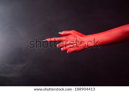 Red devil pointing hand with black sharp nails, extreme body-art, Halloween theme
