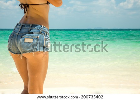 Hot beautiful woman in denim shorts on sea background