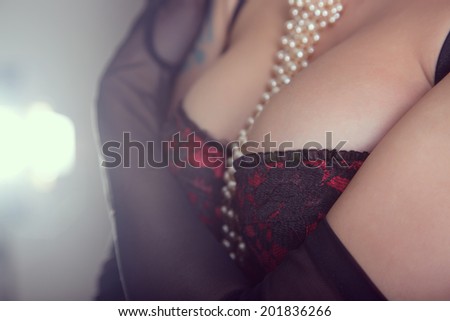Busty woman in vintage red bra and sheer gloves, studio shot
