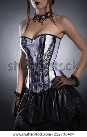 Elegant woman in black and white corset, studio shot on black background