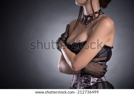 Busty woman in elegant pink and black corset with floral pattern, studio shot