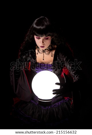 Attractive witch or fortune teller looking into a crystal ball, Halloween theme