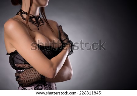 Busty woman in elegant Victorian corset embracing herself, studio shot
