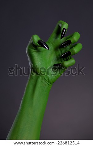 Green witch hand with sharp black nails, real body-art, Halloween theme