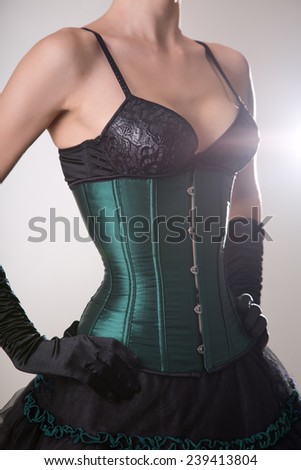 Close-up shot of beautiful young woman in green corset and black skirt