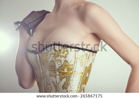 Close-up shot of sexy young woman in corset with golden embroidery, studio shot with vintage tone