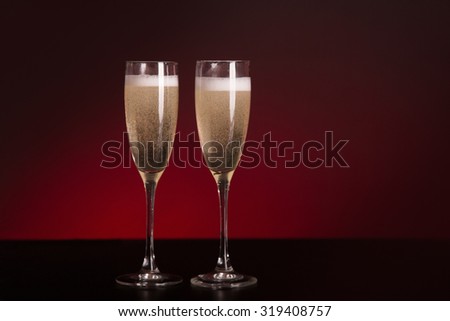 Two elegant champagne glasses, studio shot on glamorous red background
