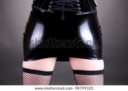 Sexy dominatrix woman in latex skirt, studio shot