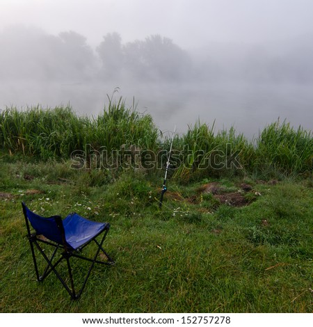 Fishing chair and a fishing rod in river at the foggy morning