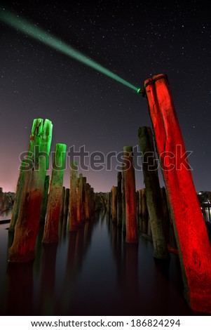 Unusual red poles in the water reflection  at night with deep stars sky