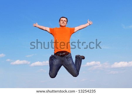Happy young man in red t-shirt jumping high at the blue clear sky background