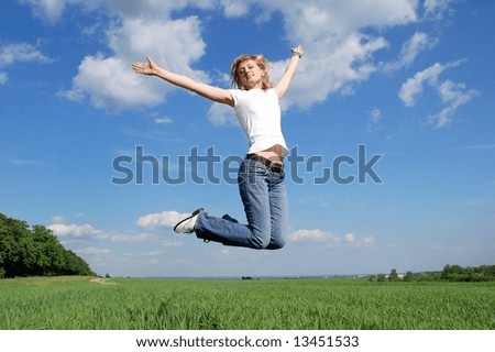 Young woman jumping at the background of blue sky and clouds in form of wings