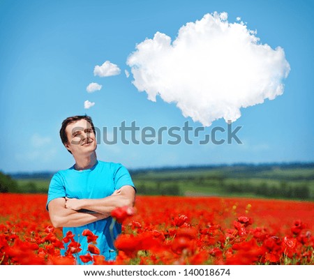 Young man standing in the poppy field and looking to the text-balloon thinking  clouds bubble in clear blue sky