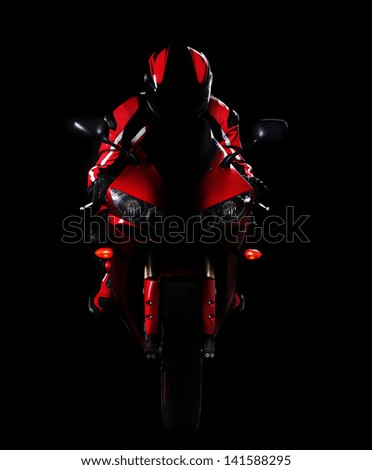 Motorcyclist in red equipment and helmet on black background low key silhouette