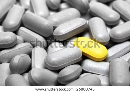 one yellow pill on gray pills background