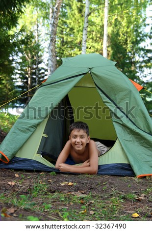 happy boy in camping tent in summer forest