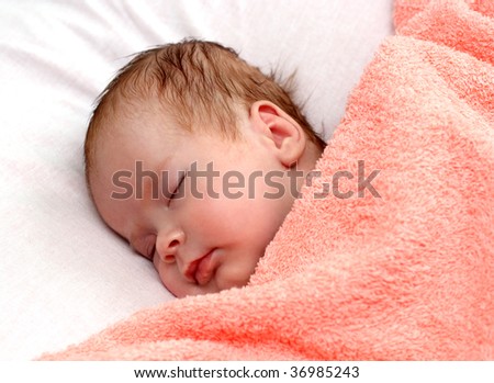 newborn baby sleeping under peachey blanket