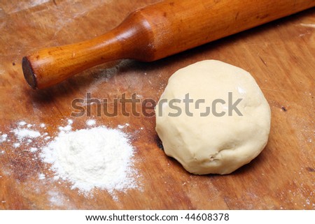 rolling-pin with pastry on wooden board