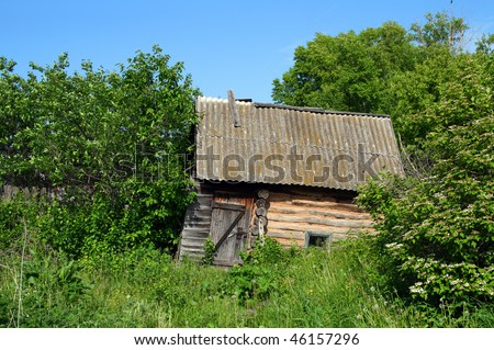old wooden obsolete bath-house in lush foliage bushes