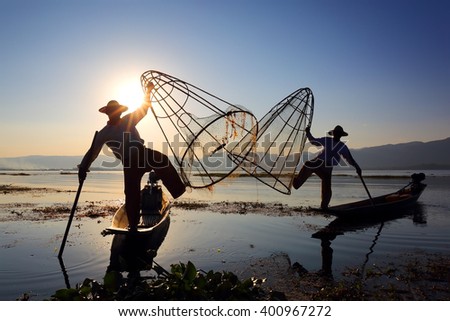 Myanmar travel attraction landmark - Traditional Burmese fishermen with fishing net at Inle lake in Myanmar famous for their distinctive one legged rowing style