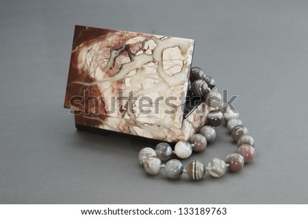 Stone box with the beads on a gray background.