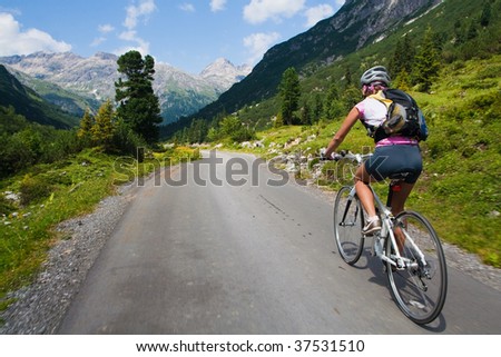 Girl riding fast on a bicycle in mountain area. Back view and motion blur