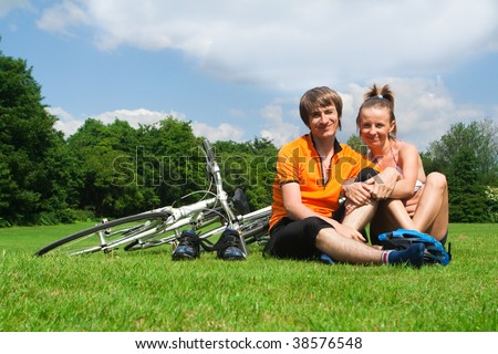 Happy young couple resting on a green meadow after bicycle trip
