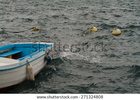 Small wooden boat in the wavy sea before the storm