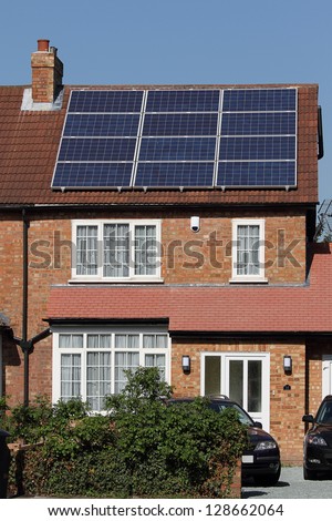 Solar photovoltaic panel array on house roof against a blue sky