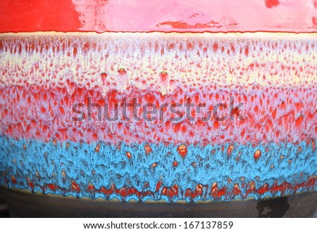 textured background under a layer of clay with shades of blue, red, white.
