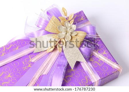 Purple and golden bow on purple gift box background