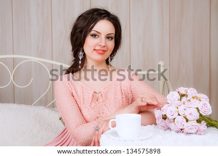 girl in a pink dress at a table with a cup of tea