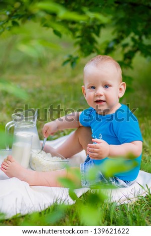 little boy in the garden with milk and cheese