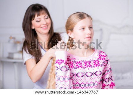 Mom combing hair of his daughter